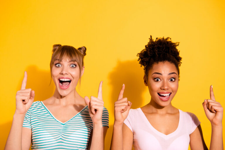 Close up photo beautiful two people she her model lady positive excited buddies fellows diversity raise index fingers up wear casual white striped t-shirt clothes isolated yellow bright background