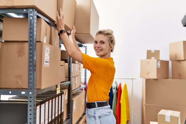 Young,Blonde,Woman,Ecommerce,Business,Worker,Organizing,Packages,On,Shelving
